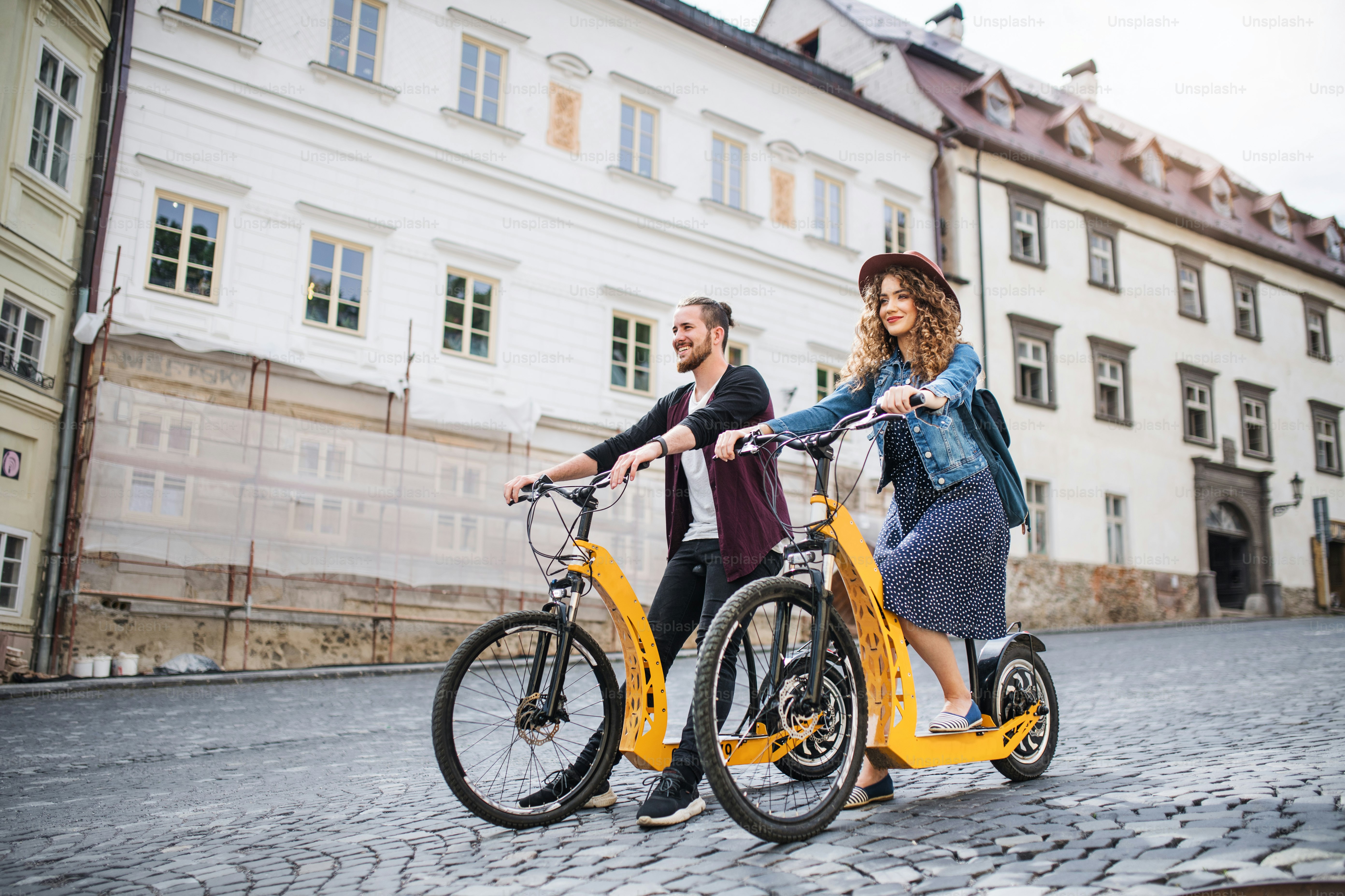 Young tourist couple travellers with electric scooters in small town, sightseeing.