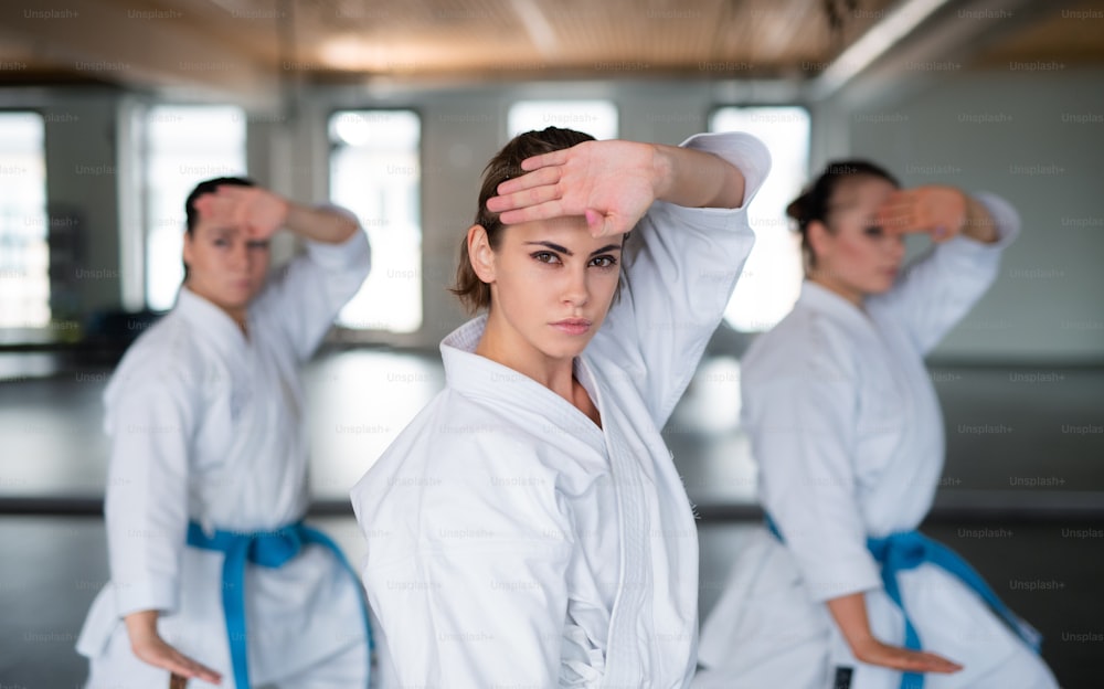 Eine Gruppe junger Frauen übt Karate drinnen im Fitnessstudio.