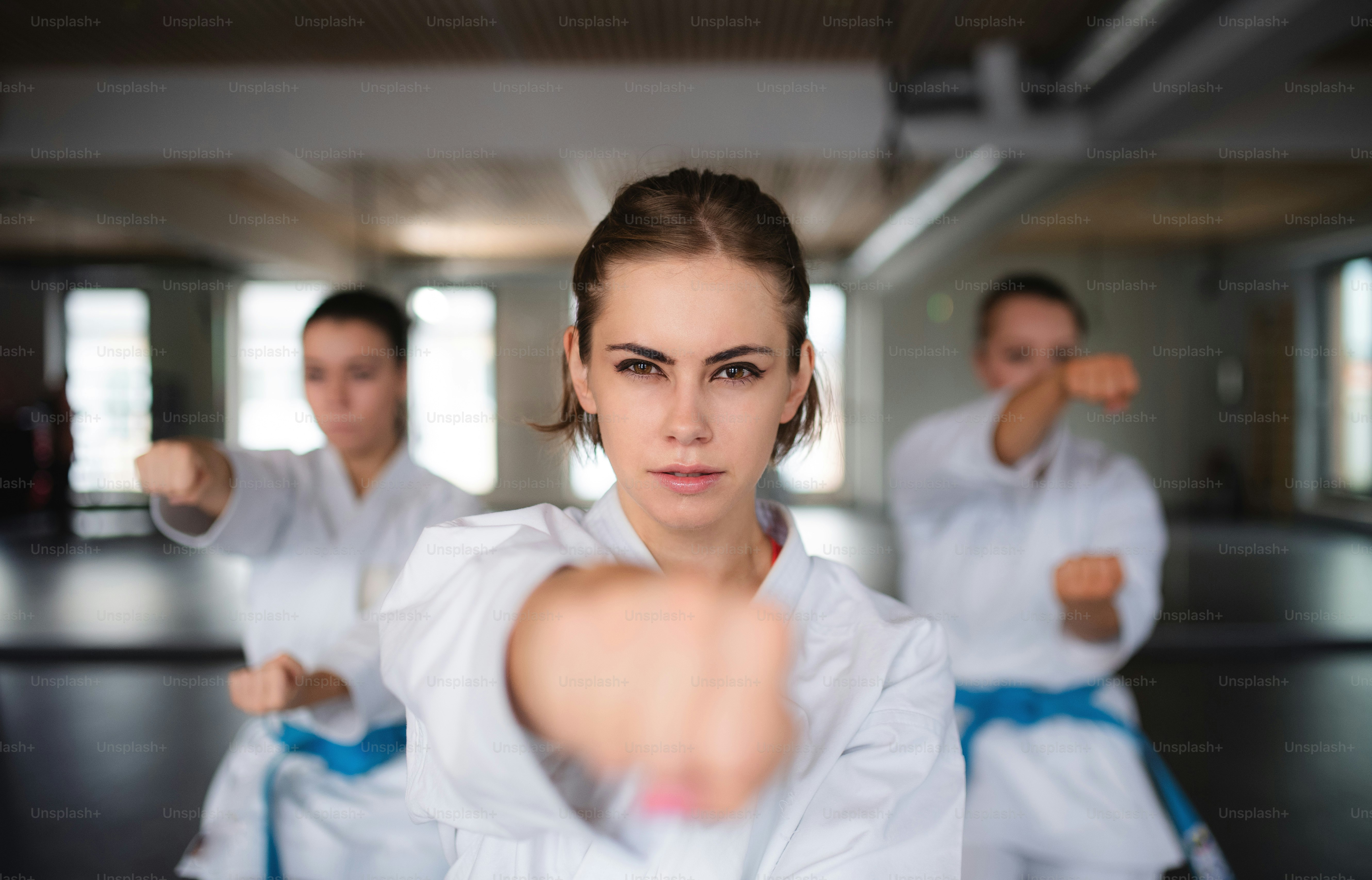 Um grupo de jovens mulheres praticando karatê dentro de casa na academia.