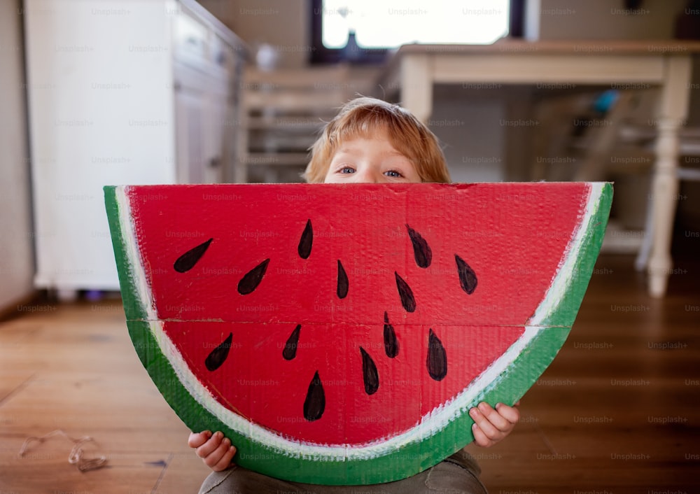 Un bambino che gioca con un grande frutto giocattolo all'interno di casa, mangiando il concetto di frutta.