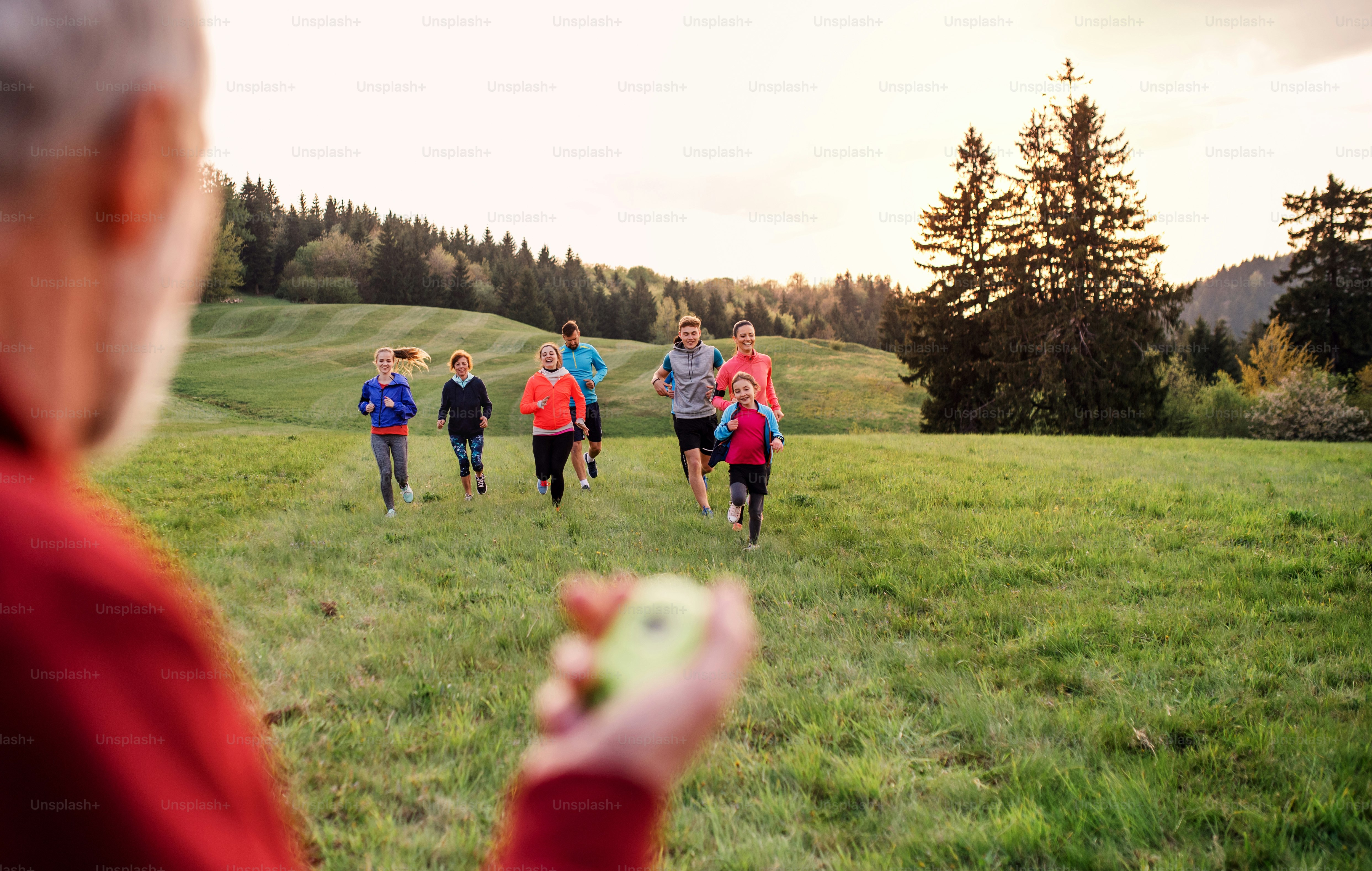 A large group of people cross country running in nature, checking time.