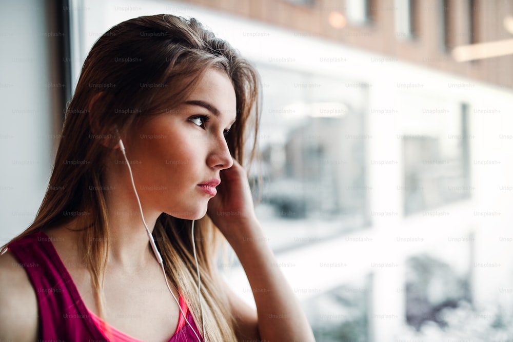 Ein Porträt eines jungen Mädchens oder einer jungen Frau mit Kopfhörern in einem Fitnessstudio. Ein Kopierbereich.