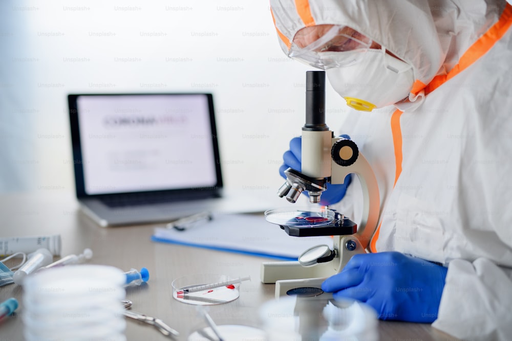 Doctor with microscope analyzing blood samples, coronavirus concept. Copy space.