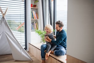 Mature father with small boy playing indoors in bedroom, playing.