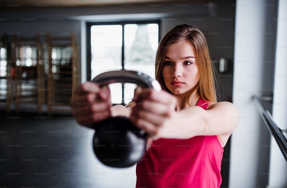 Um retrato de uma bela jovem ou mulher fazendo exercício com um kettlebell em uma academia.
