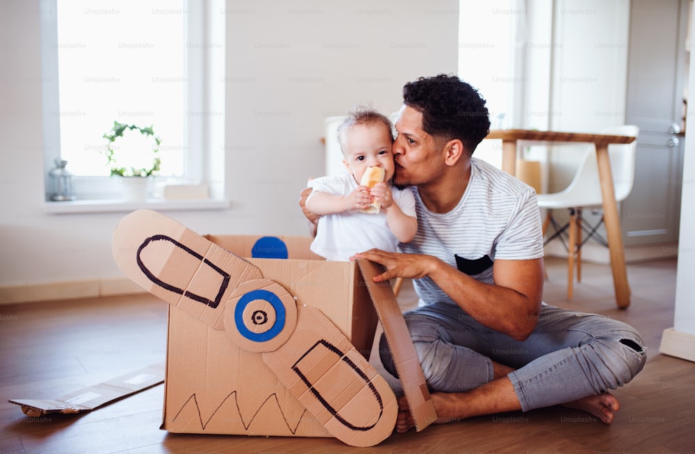 Pai alegre e filho pequeno dentro de casa, brincando.