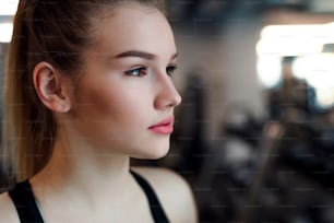 A portrait of a beautiful young girl or woman standing in a gym. Copy space.