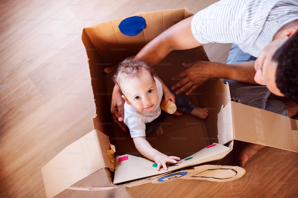 A top view of unrecognizable father and small toddler son indoors at home, playing.