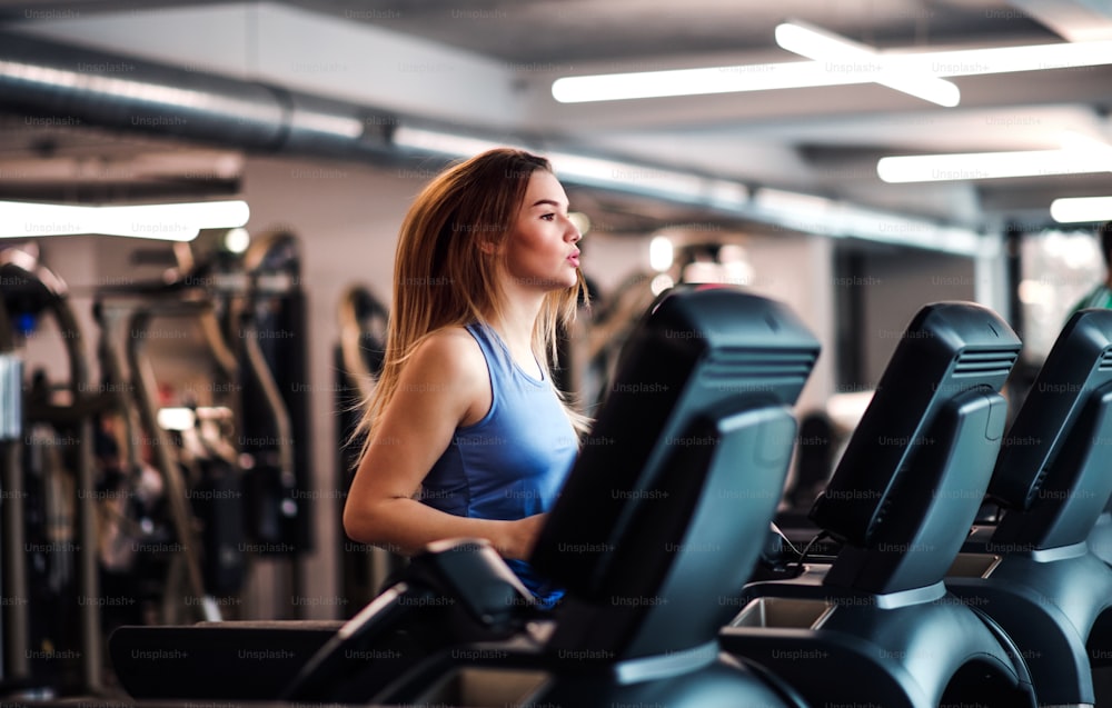 A portrait of a beautiful young girl or woman doing cardio workout in a gym.