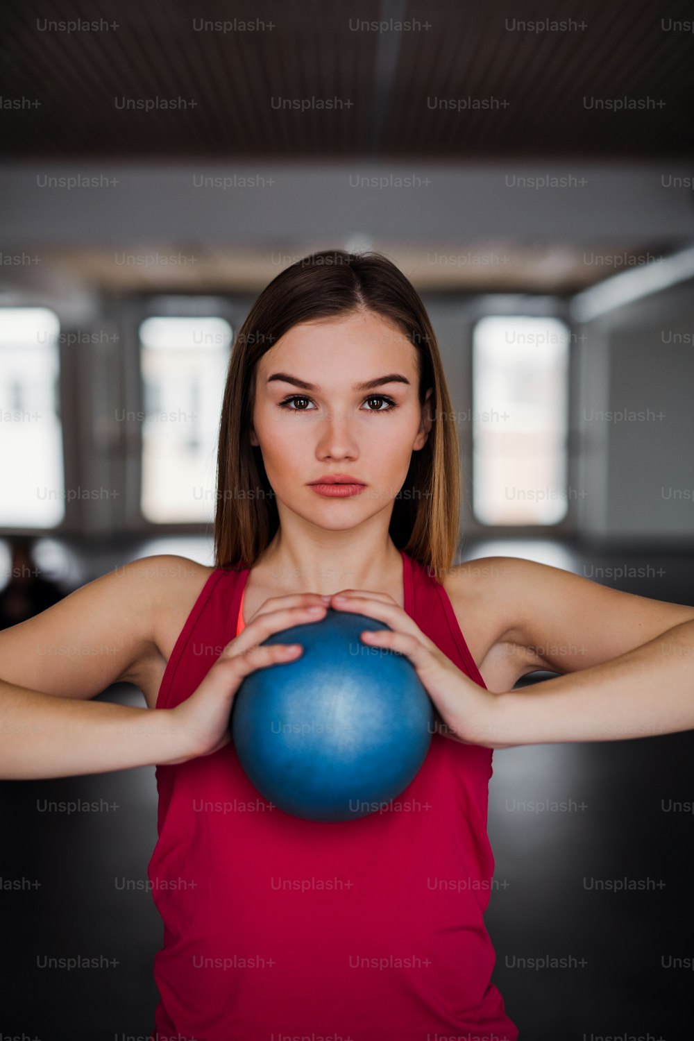 Un retrato de una hermosa joven o mujer haciendo ejercicio con una pelota en un gimnasio.