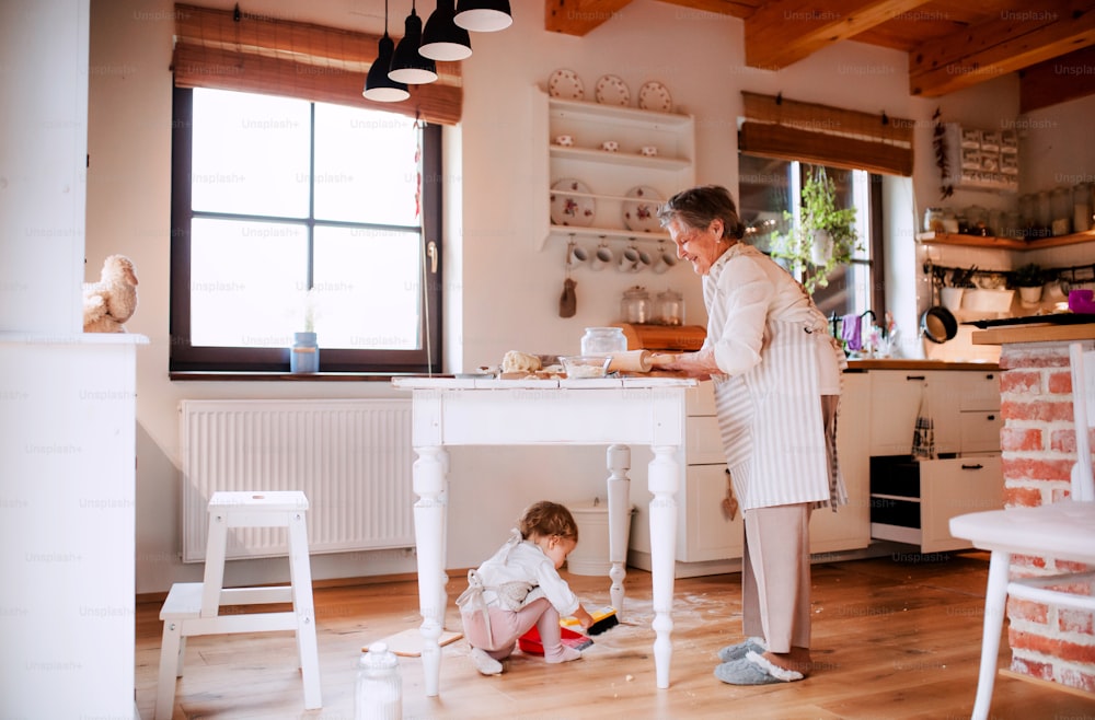 Una bisabuela mayor con un nieto pequeño haciendo pasteles en casa.