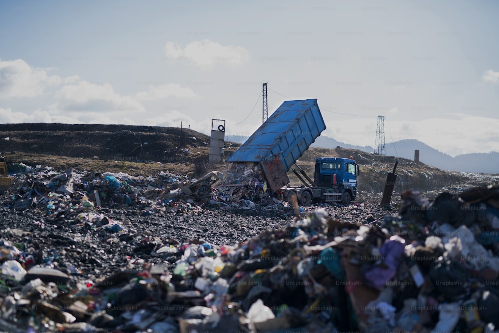 Garbage truck unloading waste on landfill, environmental concept. Copy space.