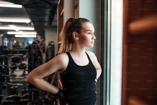 A portrait of a beautiful young girl or woman standing in a gym.