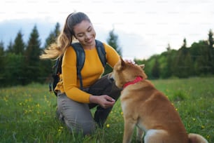夏の自然の中で屋外を散歩する犬を連れた幸せな若い女性。