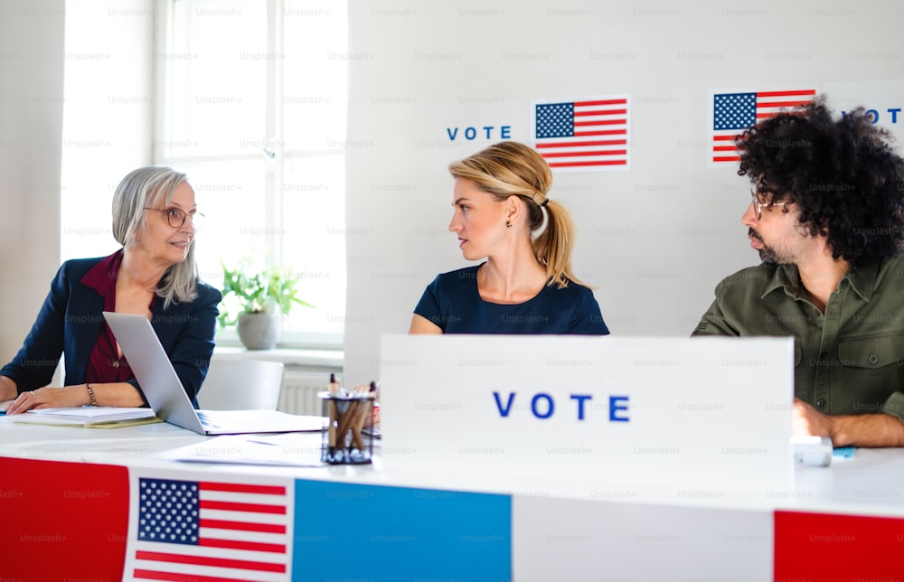 Man and women members of electoral commission talking in polling place, usa elections.
