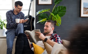 A group of young cheerful friends relaxing indoors, house sharing concept.