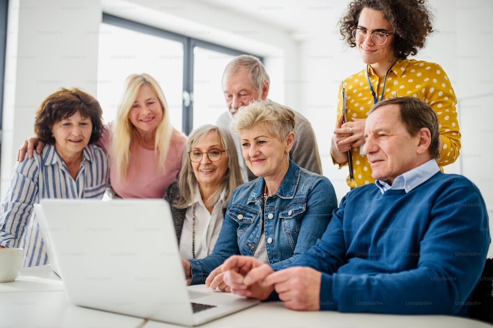 Gruppe fröhlicher älterer Menschen, die am Computer- und Technologieunterricht teilnehmen.