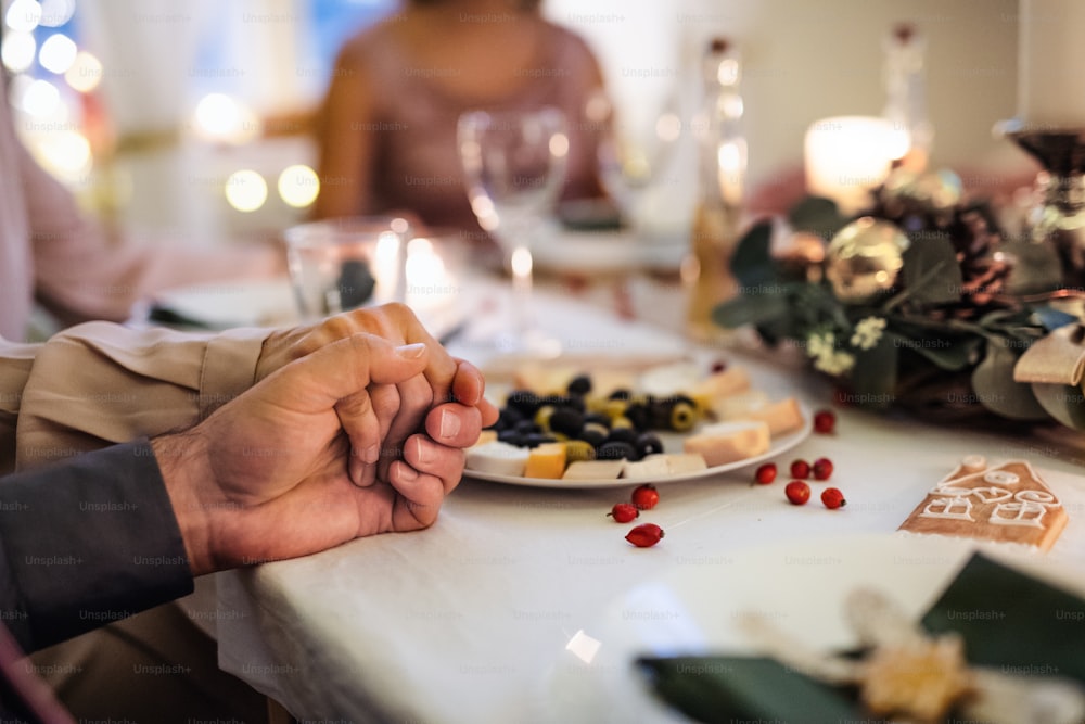 Close-up of hands holding together at the table at Christmas, detail. Praying concept.