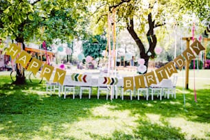 A table set for kids birthday party outdoors in garden in summer, celebration concept.