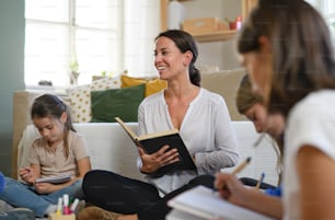 Group of homeschooling children with parent teacher studying indoors, coronavirus concept.