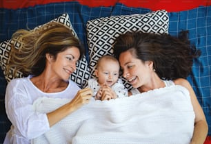 Vista superior de una mujer feliz con una hija y una nieta bebé descansando sobre una manta.