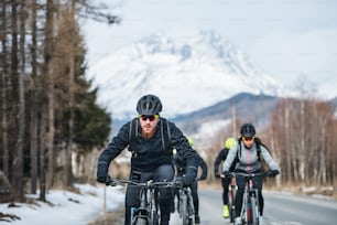 Un gruppo di giovani mountain biker che pedalano su strada all'aperto in inverno.