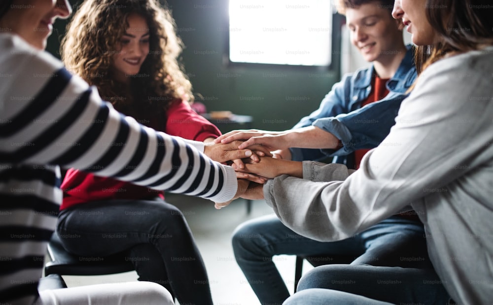 Men and women sitting in a circle during group therapy, stacking hands together.