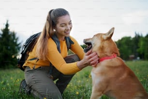 夏の自然の中で屋外を散歩する犬を連れた幸せな若い女性。