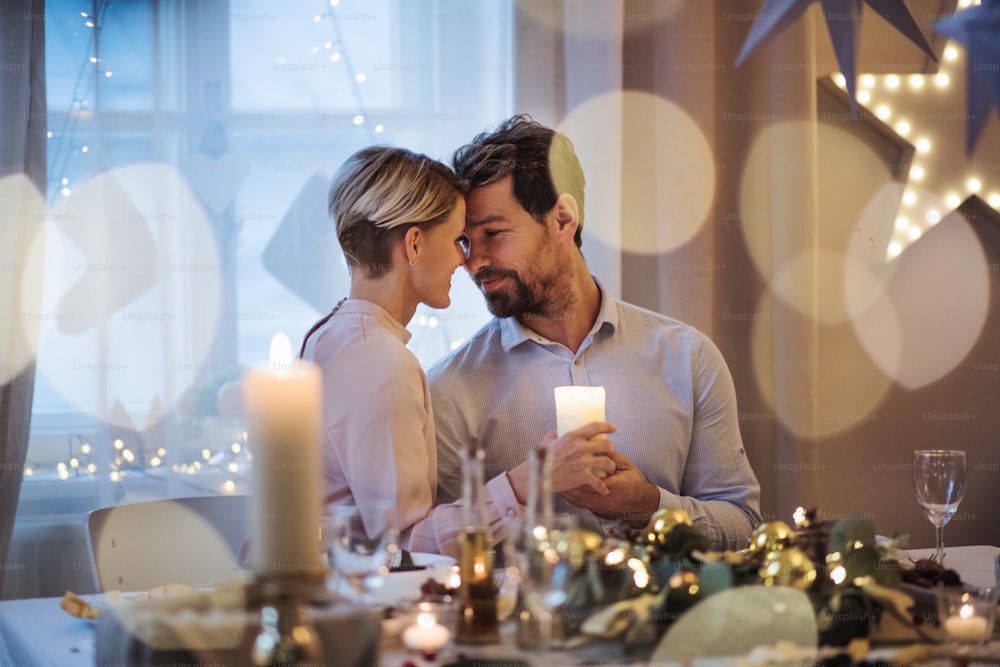 Retrato de vista frontal de una pareja feliz en el interior de la mesa celebrando la Navidad.