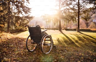 Un fauteuil roulant vide sur une pelouse dans un parc au coucher du soleil.