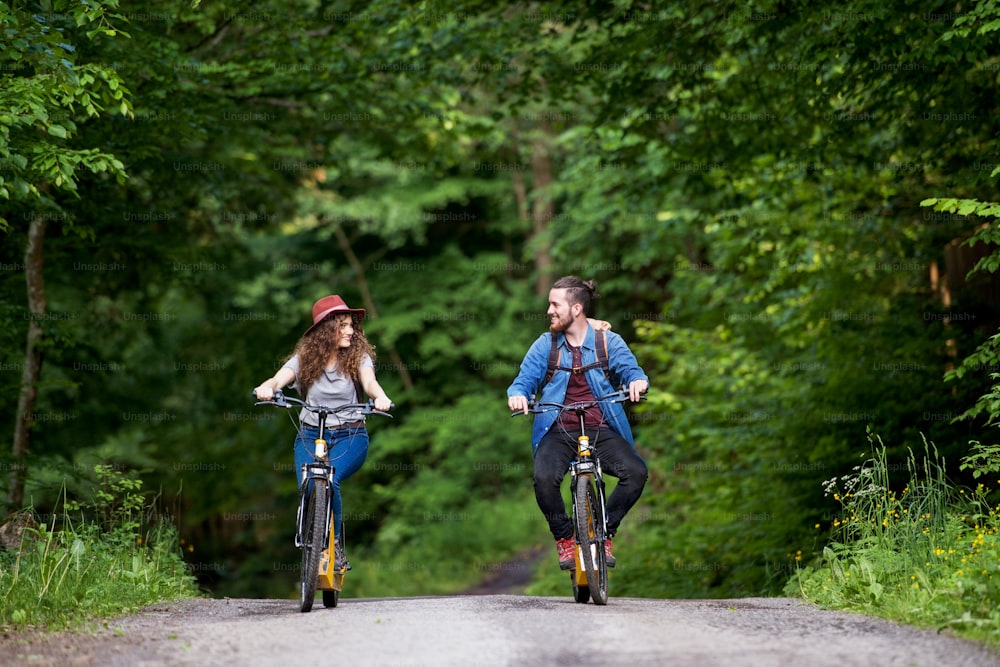 Jovens turistas casal viajantes com mochilas e scooters elétricas na natureza.