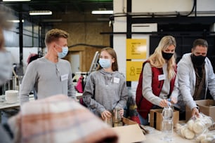 Group of volunteers working in community charity donation center, food bank and coronavirus concept.