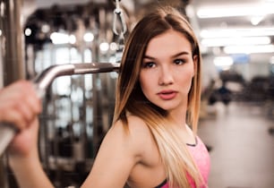Una hermosa joven o mujer haciendo entrenamiento de fuerza en un gimnasio.