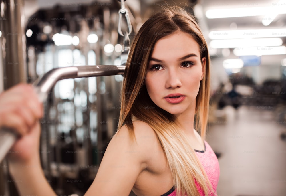 A beautiful young girl or woman doing strength workout in a gym.