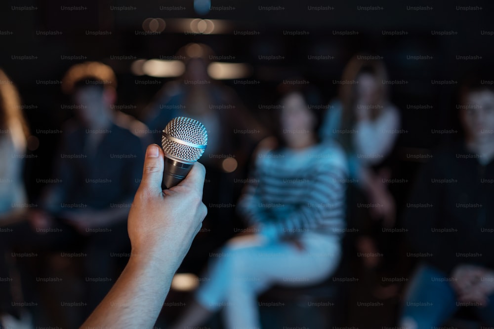 Midsection of obscured presenter holding microphone , presentation at conference concept.