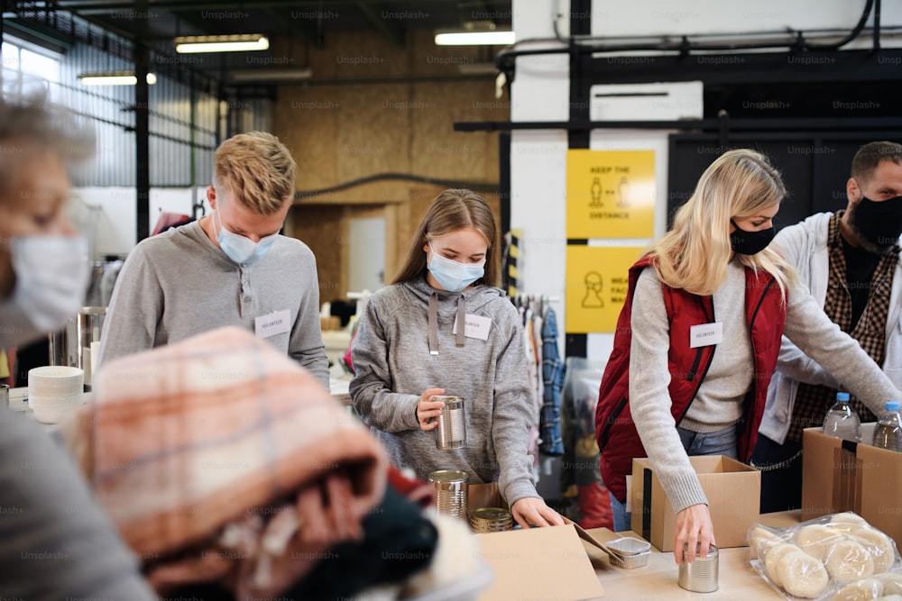 Group of volunteers working in community charity donation center, food bank and coronavirus concept.