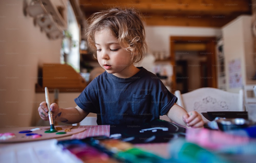 Ein konzentriertes kleines Mädchen, das zu Hause Bilder malt, in der Freizeit.