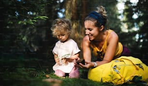 Porträt einer glücklichen Mutter mit kleiner Tochter im Freien in der Sommernatur, die sich im Wald ausruht.