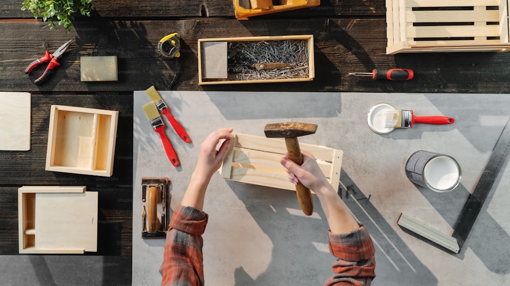 A top view of unrecognizable woman making wooden boxes, small business and desktop concept.