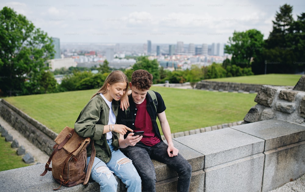 Portrait of young couple travelers in city on holiday, using smartphone.