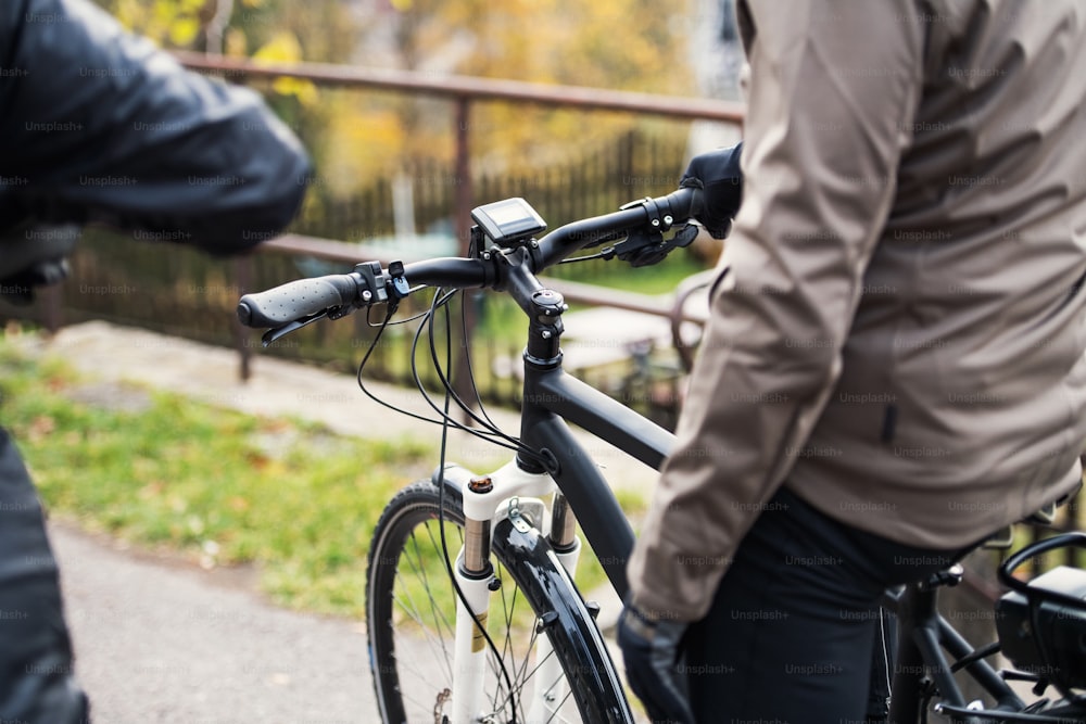 ヘルメットと電動自転車を身に着けたアクティブなシニアカップルが屋外の道路をサイクリングしている中央部。
