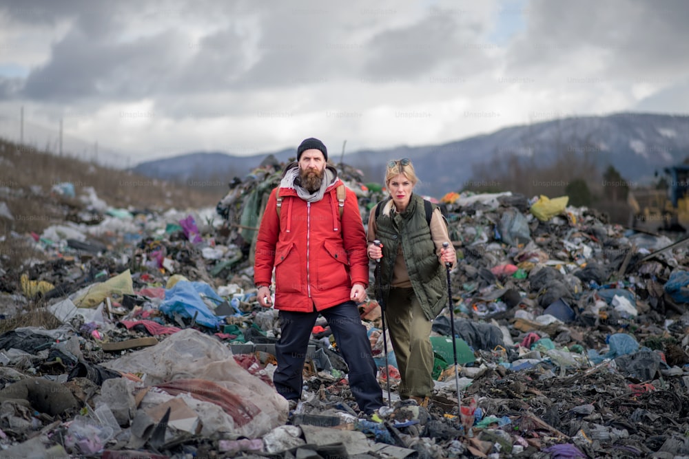 Man and woman hikers on landfill, environmental and pollution concept.