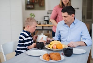 ダウン症の息子と幸せな家族が食卓を囲み、朝食をとっている。