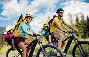 Happy family with small children cycling outdoors in summer nature, High Tatras in Slovakia.