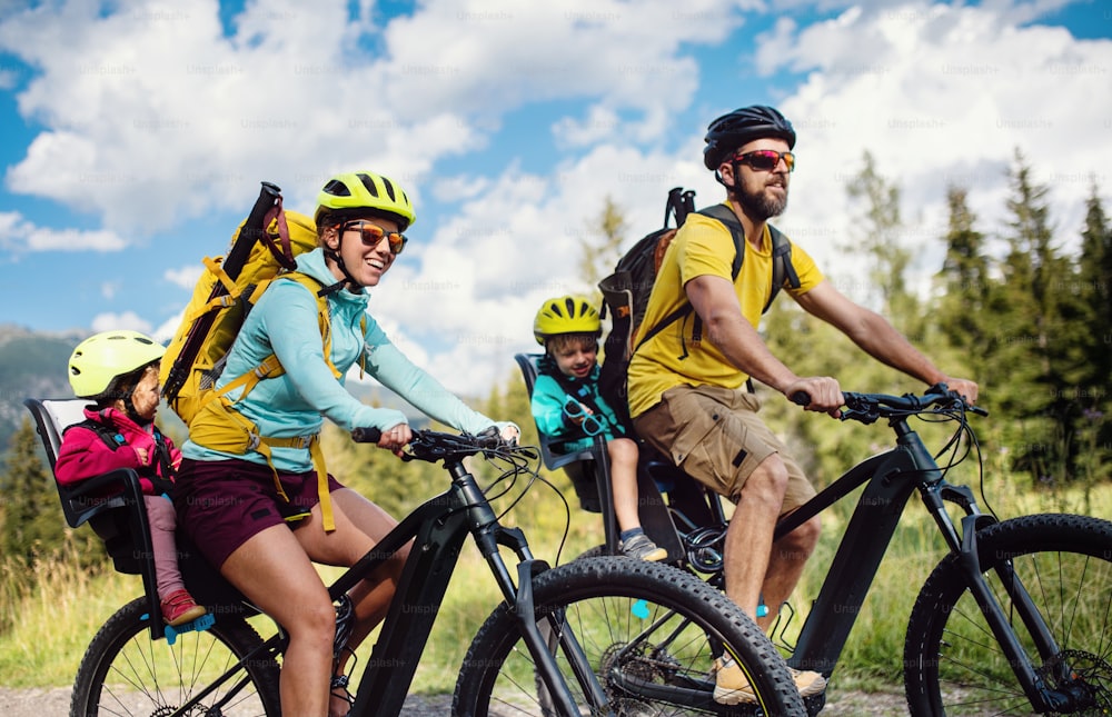 Happy family with small children cycling outdoors in summer nature, High Tatras in Slovakia.