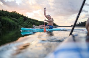 Vista frontal de un hombre mayor que practica paddleboarding en el lago en verano. Espacio de copia.