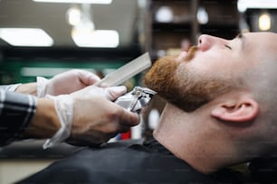 Un giovane cliente in visita al parrucchiere nel negozio di barbiere, nella sezione centrale e nel primo piano.