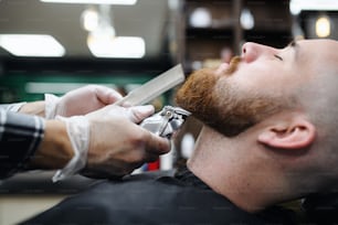 A young man client visiting haidresser in barber shop, midsection and close-up.