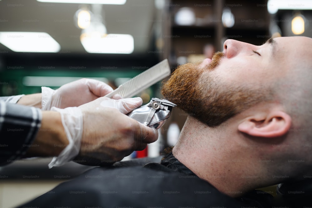Um jovem cliente visitando haidresser em barbearia, midsection e close-up.
