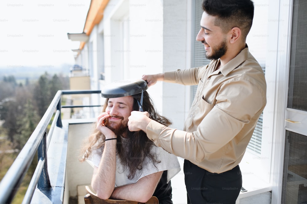 Haircut on balcony at home, coronavirus, lockdown, friendship and fun concept.